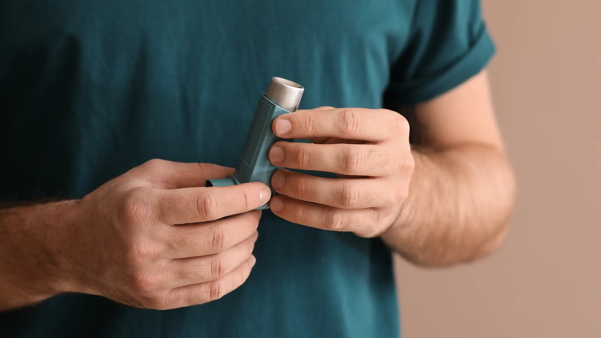 Ein Mann hält einen Inhalator in der Hand.